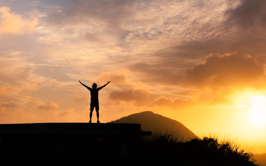 Success achievement accomplishment and motivation concept with man sunset silhouette celebrating arms up raised outstretched trekking climbing outdoors in nature 	