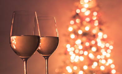 Romantic New year Christmas background. Pair of wine glasses next to Christmas tree. 