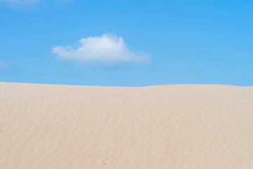 Fototapeta na wymiar Lonely cloud over a dessert dune against blue sky