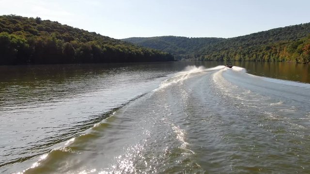 Aerial shot following a man water skiing and a motorboat in Raystown lake, Pennsylvania.
