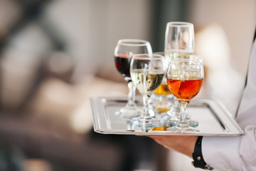 Waiter serving glasses of cold beer, soft drinks and white wine on the tray at a business meeting