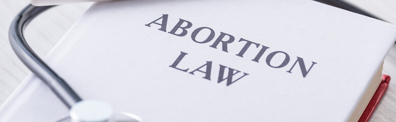 panoramic shot of book with abortion law lettering near stethoscope