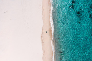 Aerial view on the couple walking on the beautiful beach on Sardegna Italy