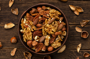 hazelnut almonds pecan nuts in bowl on wooden table background with shell