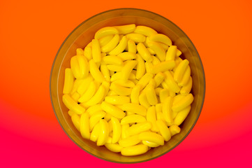 Multiple yellow banana candies on a circular, plastic plate .