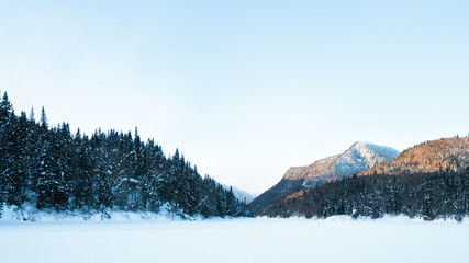 Fototapeta premium Jacques-Cartier National Parc, Qc. Canada. View of the Valley in winter from the covered river 16x9. Vallée de la Jacques-Cartier en hiver avec montagnes 16x9