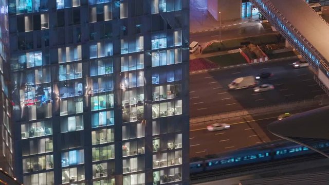 Night view of office and apartment building with traffic on highway. High rise skyscraper with blinking windows with people moving inside. Aerial view from above.