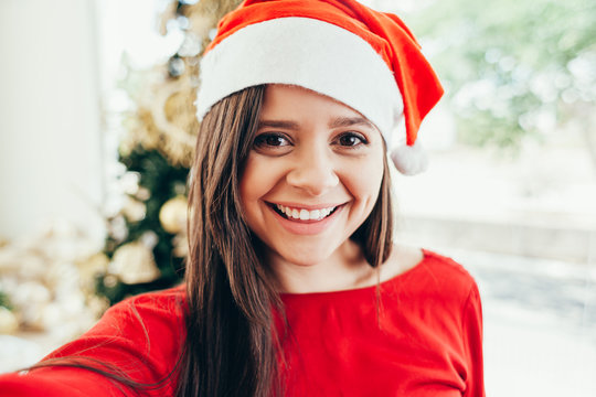 Cheerful young woman taking a Christmas selfie with smartphone.