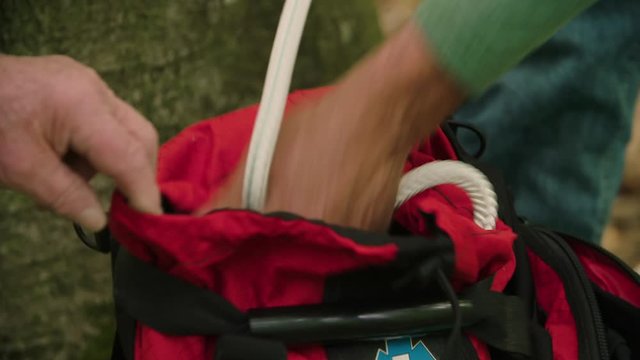 Closeup Insert: A conservationist repacks a tree climbing rope into a bag