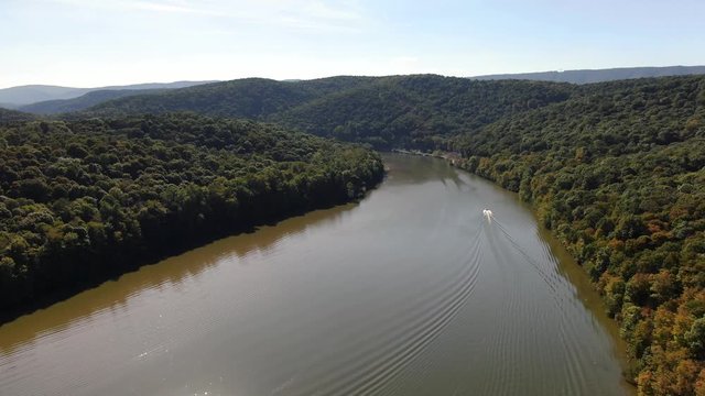 High aerial view of Raystown Lake while following a motorboat with a man water skiing in Pennsylvania.