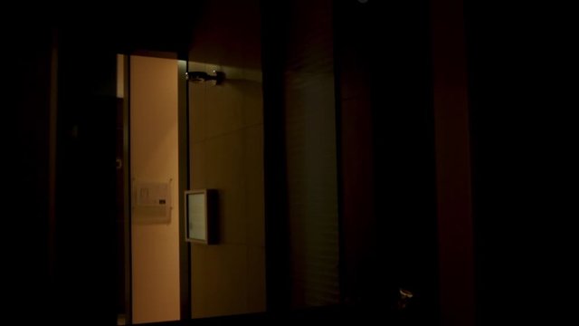 A light gets switched of in a modern bathroom. Caucasian hands on the switch. Indirect light in the mirror.