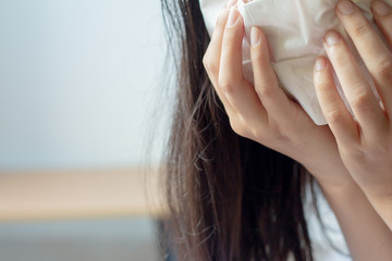 Close up sick young woman has runny nose, blowing her nose into paper.common cold, flu, allergies,...