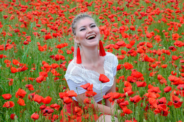 girl sat in the middle of a poppy field.
