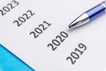 List of recent years on white paper. Pen points at 2020. Copy Space