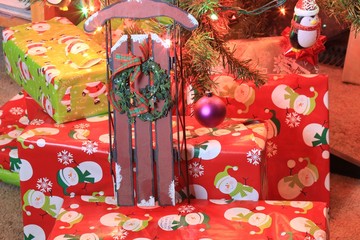 Christmas gifts on red background with a sled and wreath.