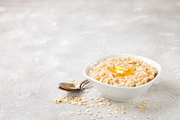 Porridge with oil in a bowl on a gray concrete background. Healthy useful breakfast. Selective focus. Copy space