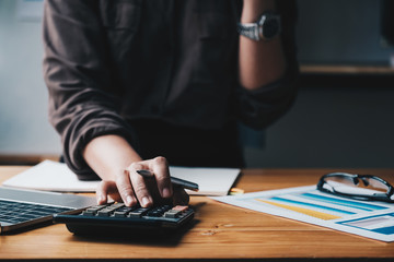 Business woman entrepreneur using a calculator with a pen in her hand, calculating financial expense.