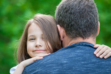 Portrait of cute little girl held in father arms. Happy loving family. Father and his daughter child girl playing hugging. Cute baby and daddy. Concept of Father day.  Family holiday and togetherness