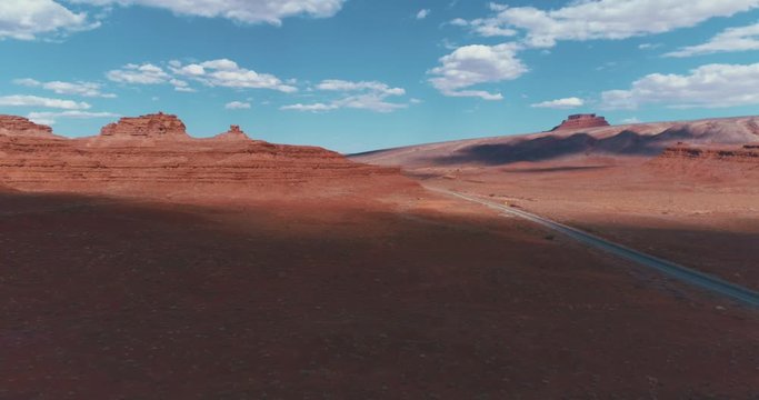 4K UHD DJI Drone Aerial of the famous Monument Valley Navajo National Indian Reserve Park in Utah / Arizona, USA with blue sky and clouds above the red soil.