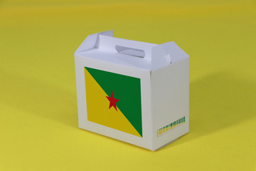 French Guiana flag on white box with barcode and the color of nation flag on yellow background. The concept of export trading from French Guiana.