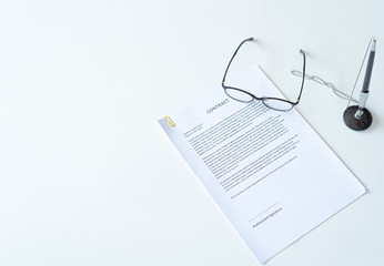 White table with paper contract detail and empty space to sign authorized signature, props with glasses and ink pen, copy space available for text