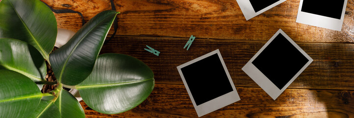 Top view of blank photographs next to a camera on a wooden table. The concept of pleasant memories. Banner.