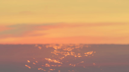 3D Rendering of wavy ocean surface with orange light reflection from cloudy sky during sunset. Depth of field applied. Provide feeling of calm, sad, lonely, peace, alone.