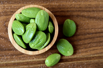 Bitter bean or stinky bean on wooden bowl for cooking, Sato seeds isolated on white background.