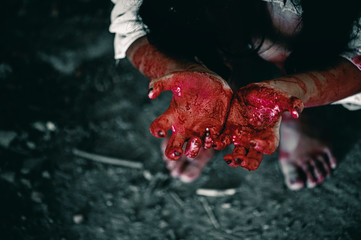 Horror Scene of a Woman with bloody hands sitting in abandoned building, Halloween murder concept.