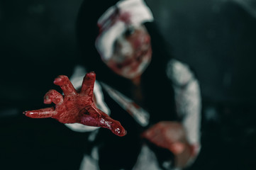 Horror ghost woman stretches her hand with resentment, has blood in hand, Halloween murder concept.