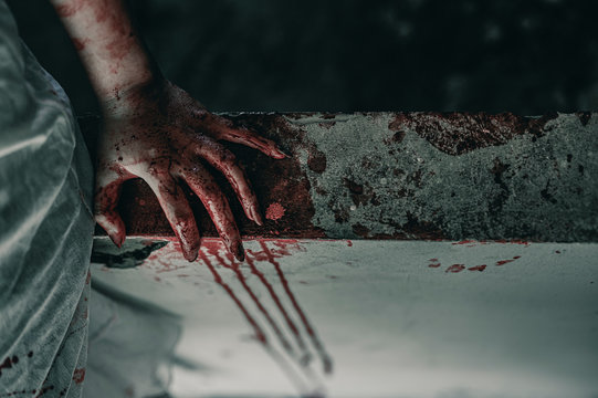 Horror Scene of a Woman with bloody hands sitting in abandoned building, Halloween murder concept.