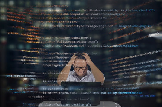 An angry and tired web designer giving an angry emotion and body gestures while working in front of his laptop. Thinking lots of HTML codes concept. Working late night in the office. 