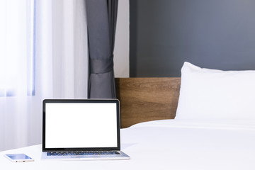 Laptop computer with blank screen with smart phone on white bed decoration in hotel bedroom interior background,Work and business in leisure with travel in the holiday concept.