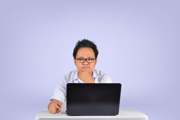 A young typical Asian student wearing white polo school uniform with eye glasses giving a focused and thinking facial expression while rubbing chin in white isolated background. 