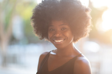 Portrait of smiling young black woman with sunlight flare and copy space