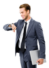Busy businessman with notebook, looking at watch, in black confident style suit, isolated against white background. Success in business, job and education concept shot.