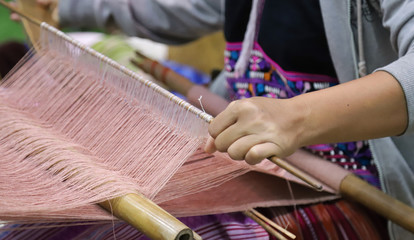 Closeup of skillful woman's hand doing colorful cotton cloth weaving.