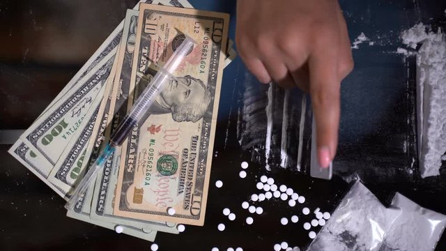 White cocaine powder on a table with dollar bills and a syringe