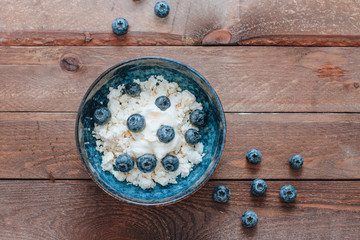 Obraz na płótnie Canvas cottage cheese in a bowl with blueberries and honey for breakfast on wooden background. top view