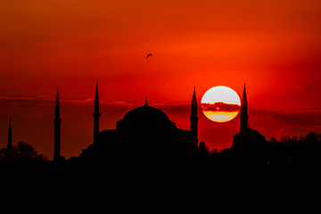 Obraz premium Cityscape of Istanbul with silhouettes of ancient mosques and minarets at sunset. Panoramic view, The Maiden's Tower, Galata Tower, Hagia Sophia, The Blue Mosque and Topkapı Palace in Istanbul.