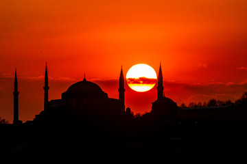 Obraz premium Cityscape of Istanbul with silhouettes of ancient mosques and minarets at sunset. Panoramic view, The Maiden's Tower, Galata Tower, Hagia Sophia, The Blue Mosque and Topkapı Palace in Istanbul.