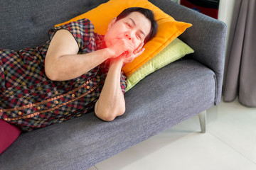 Obraz premium Elderly Asian woman coughing and lying on sofa at home,Female sore throat,Concept of health