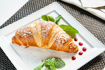 fresh croissant and cappuccino on table