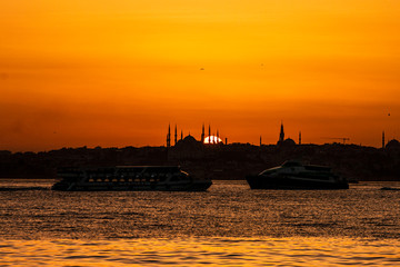 Cityscape of Istanbul with silhouettes of ancient mosques and minarets at sunset. Panoramic view, The Maiden's Tower, Galata Tower, Hagia Sophia, The Blue Mosque and Topkapı Palace in Istanbul.