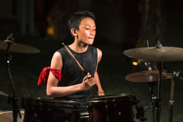 Asian American mixed teenager playing drums at home garden . cool and handsome young boy practicing...