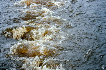 Top view of the seething water from the operation of the ship's propeller. The dark waters of the river seethe behind the ship on a summer day.