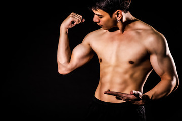 Fototapeta na wymiar sport man standing showing muscle bodybuilding on black backgrounds, fitness concept, sport concept