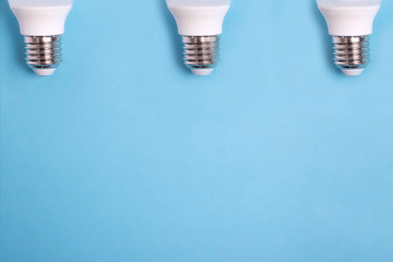 three led light bulbs on blue background flat lay