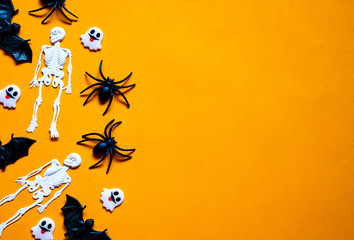Halloween holiday concept, Bats, white skeletons, black spiders and tiny ghost in orange background with copy space for text, Top flat view wallpaper