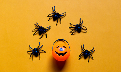 Halloween holiday concept, Spooky pumpkin bucket and spiders in orange background with copy space for text, Top flat view wallpaper